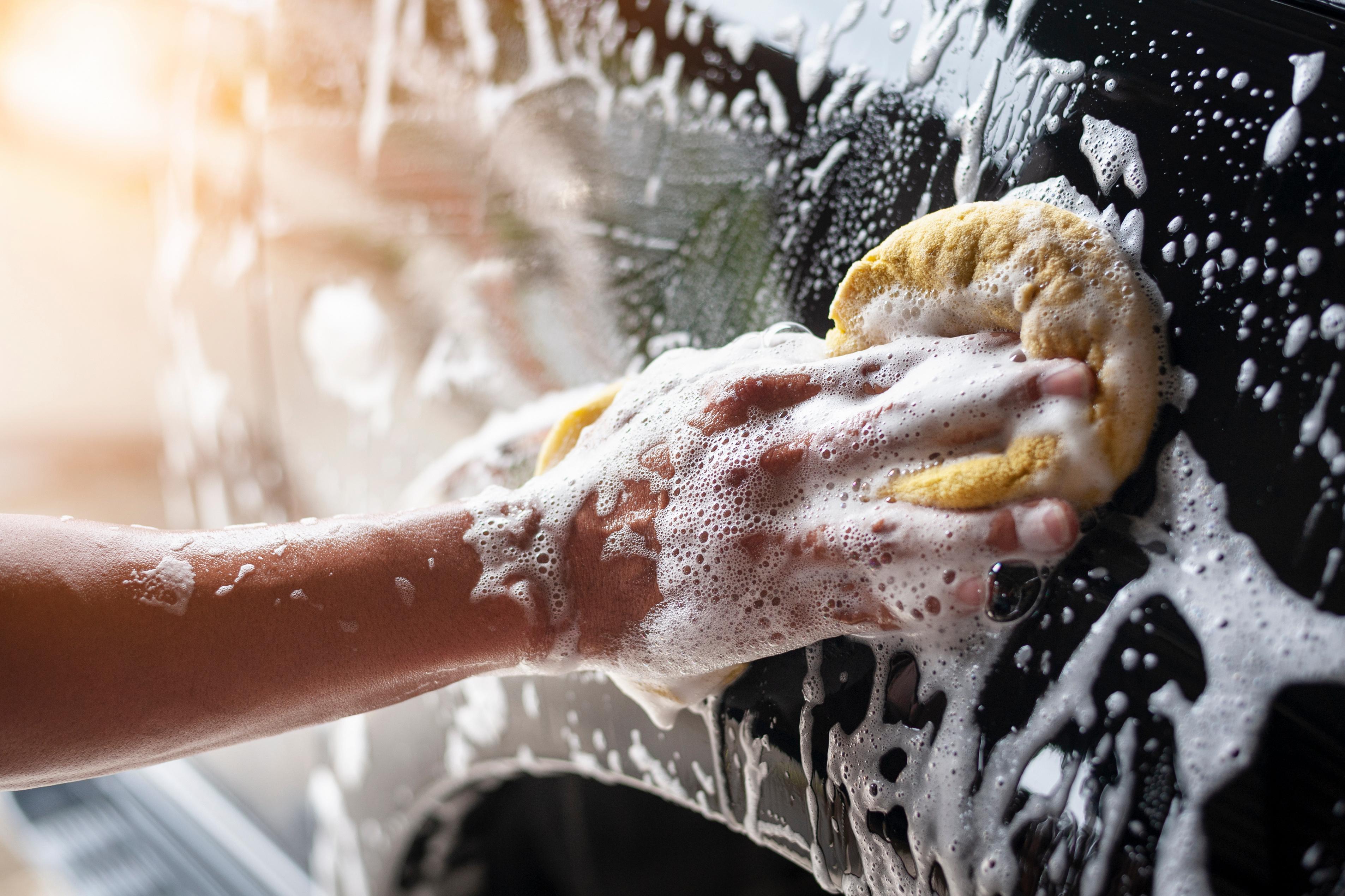 Driver cleans car with a sponge