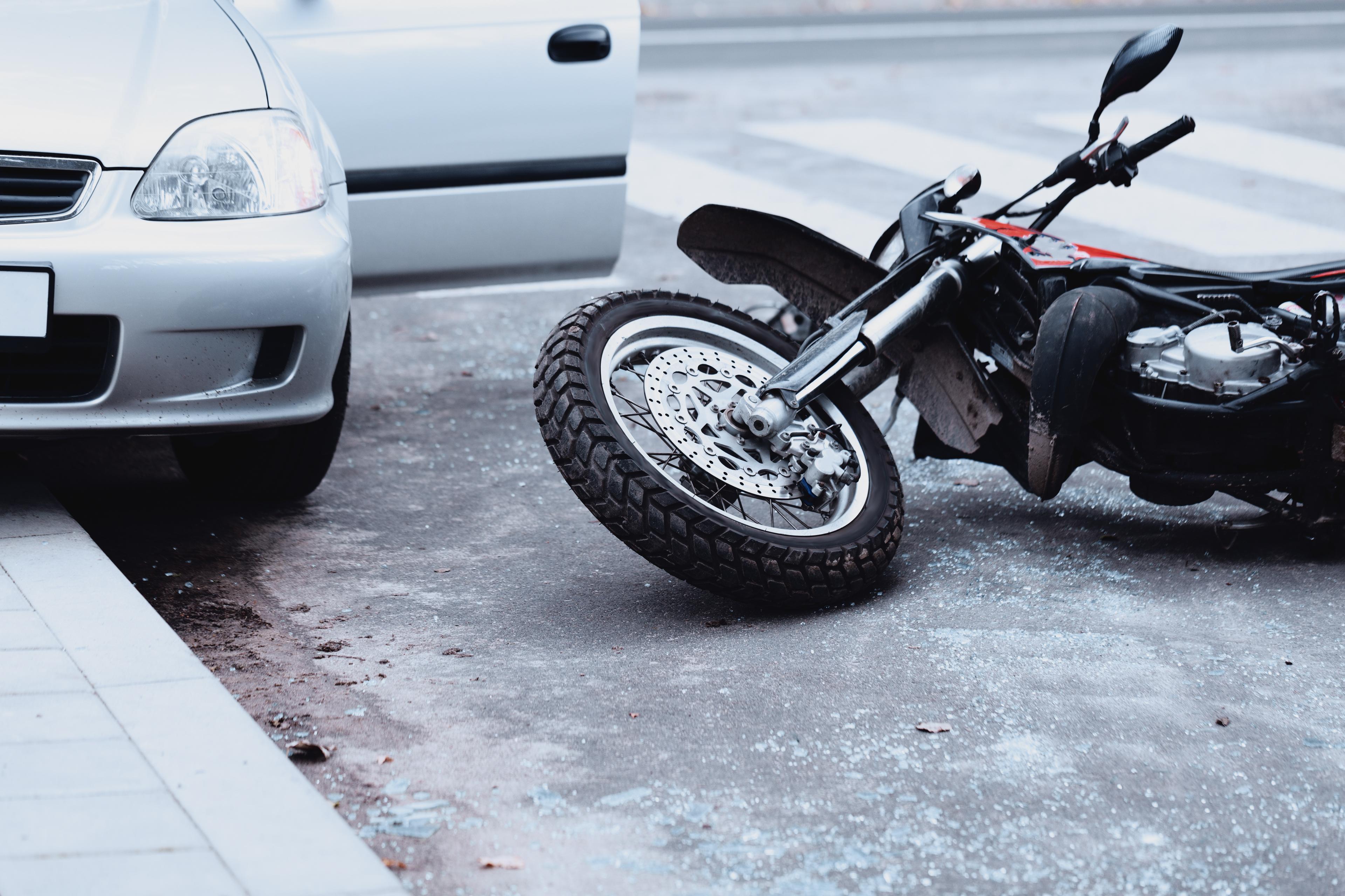 A bike lays on the road next to an open car door