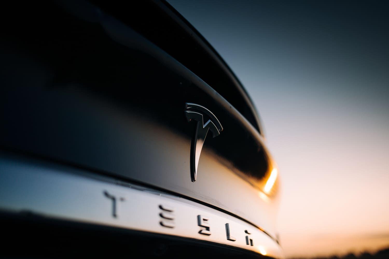 Back of a Tesla car with the sun in the background