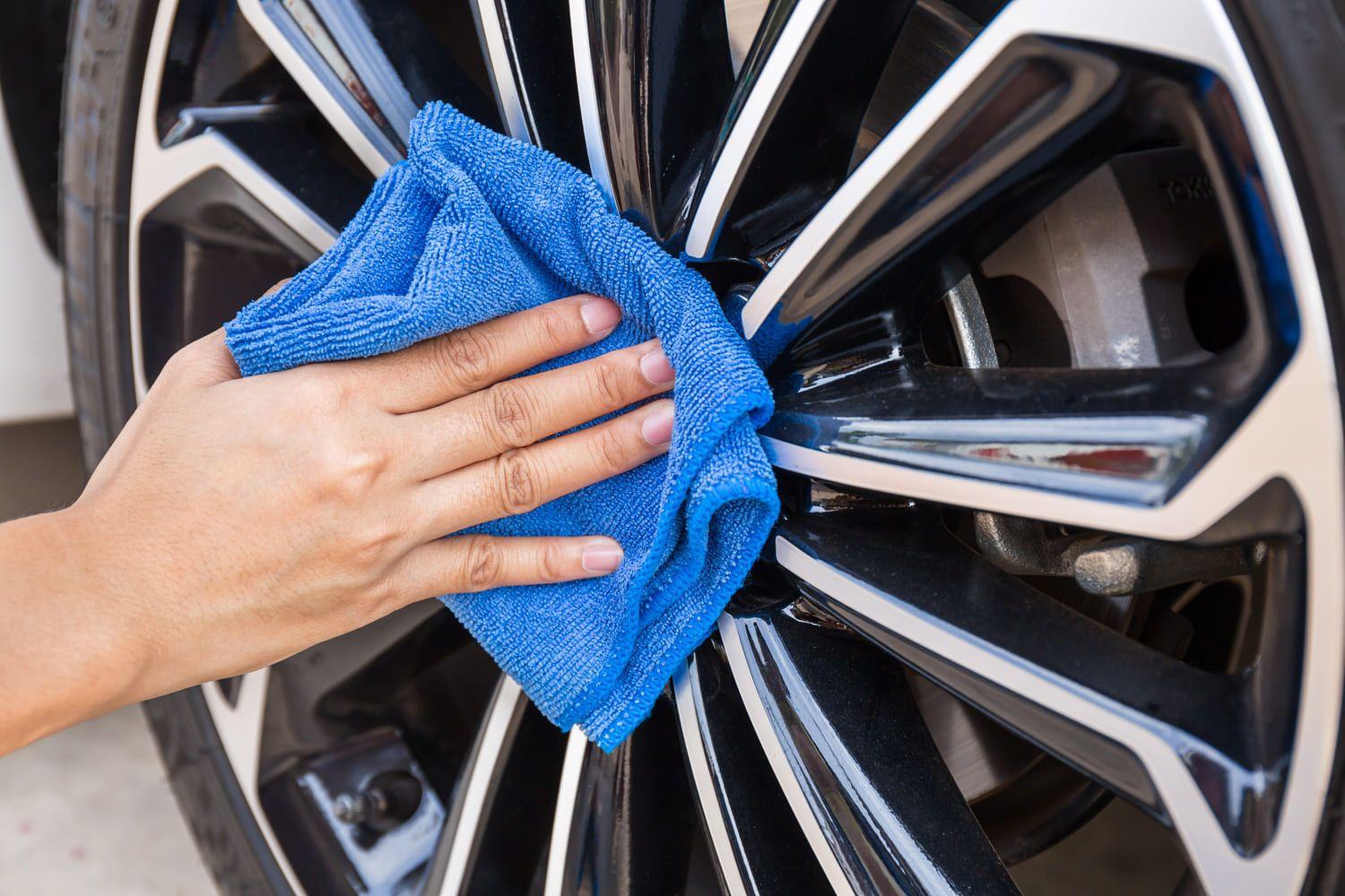 Cleaning car wheel with a blue cloth