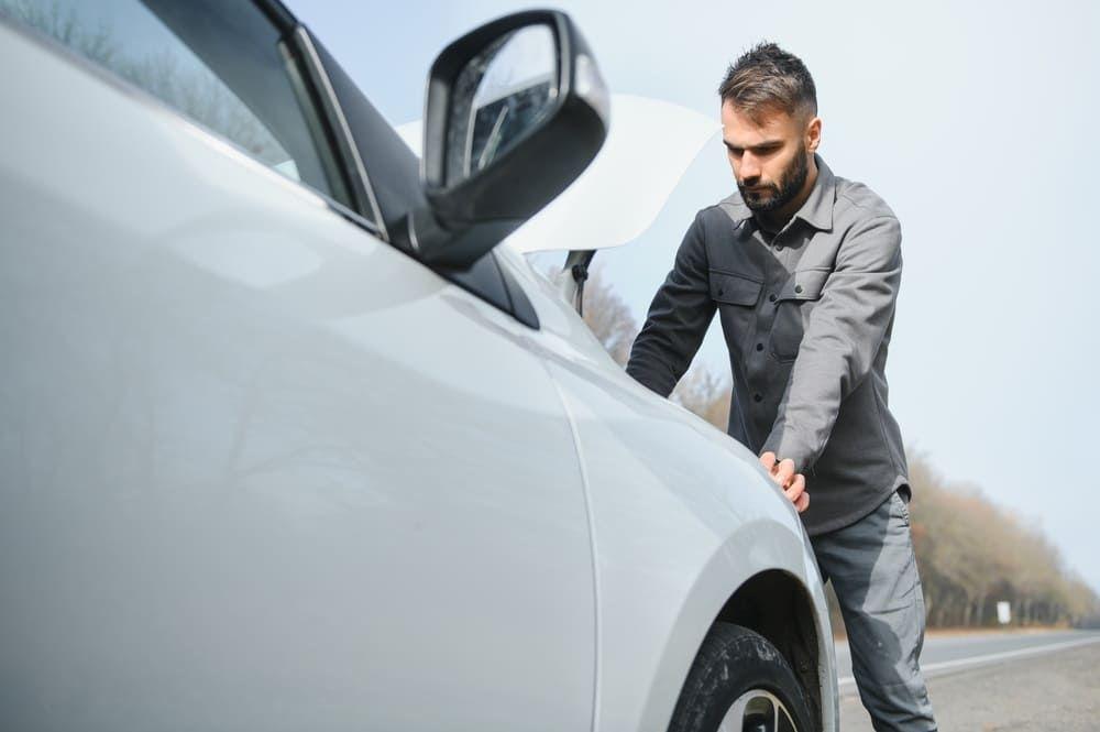 Man looks at car engine after a breakdown