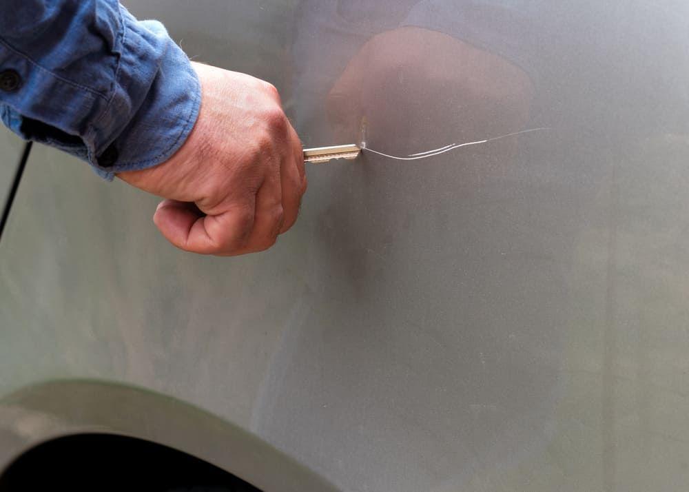 Person scratches a car with a car key